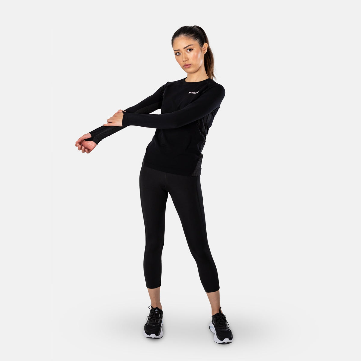 Woman stretching in the black STATSports long sleeve baselayer and leggings