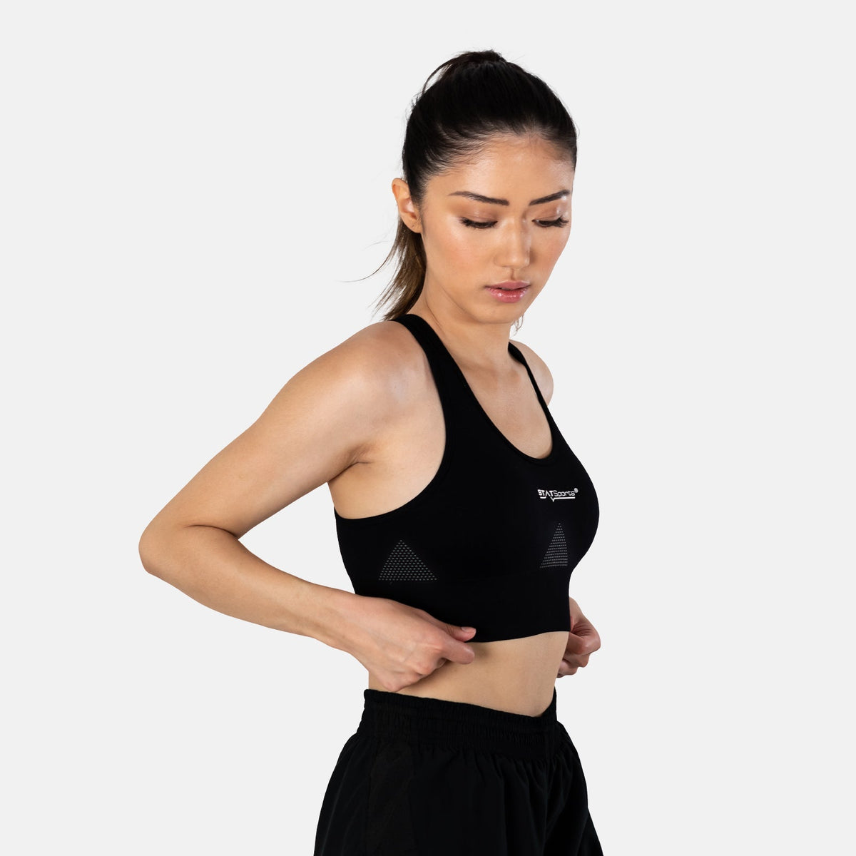 Woman wearing the black STATSports sports bra, side three-quarter view